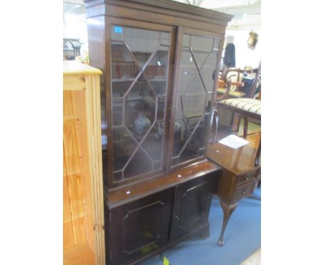 A reproduction mahogany bookcase with dentil moulded cornice, glazed doors, cupboards below on ogee bracket feet, of no comme