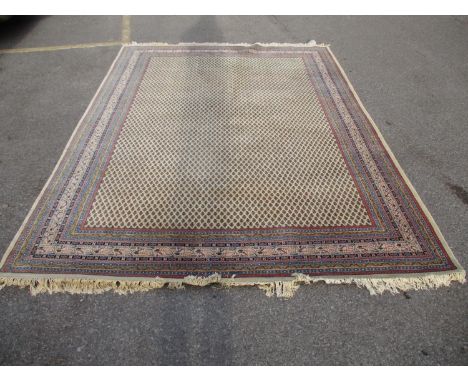 An Indian carpet with repeated boteh on a cream ground within a red, blue and yellow border, 100 x 135 