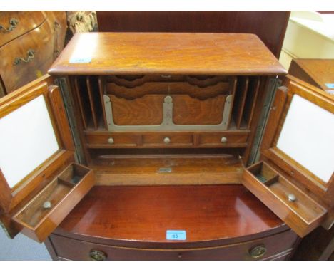 An early 20th century oak table top stationary cabinet with a hinged top over twin doors, enclosing compartments, three drawe