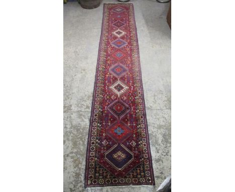 A Persian runner with eleven medallions and geometric motifs on a red ground 