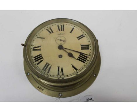 A brass bulkhead clock, white enamel dial, the case 27cm diameter and stamped '8219'Some general surface wear, small dents, e