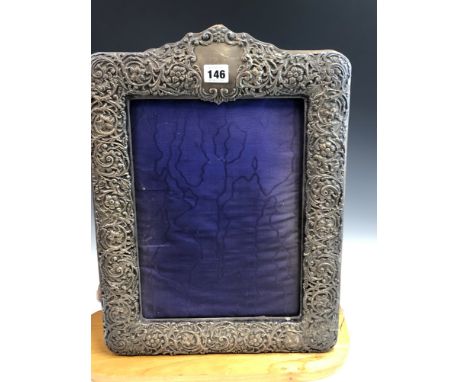 A SILVER MOUNTED VELVET EASEL BACKED FRAME BY HENRY MATTHEWS, BIRMINGHAM 1904, THE SCROLLING FOLIAGE CENTRED BY FLOWER HEADS,