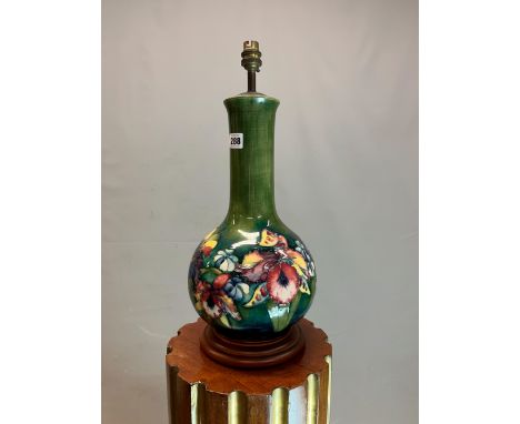 A MOORCROFT VASE AS A TABLE LAMP, THE SHADED GREEN GROUND BOTTLE SHAPE SLIP TRAILED WITH IRISES AND OTHER FLOWERS. H 49cms. W