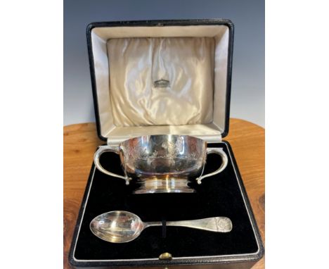 A CASED SILVER TWO HANDLED CHRISTENING BOWL AND SPOON BY ATKINSON BROTHERS, BIRMINGHAM 1935, THE RIM BAND DEPICTING HENS AND 