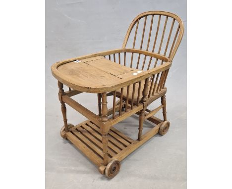 A CHILDS PUSH ALONG STICK BACK CHAIR AND TABLE, THE BASE WITH WOODEN WHEELS.