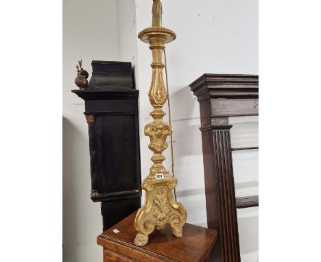 A BAROQUE STYLE GILT AND CARVED WOOD CANDLESTICK LAMP, THE BASE WITH THREE BRACKET LEGS CENTRED BY LEAVES ABOVE THE PAW FEET.
