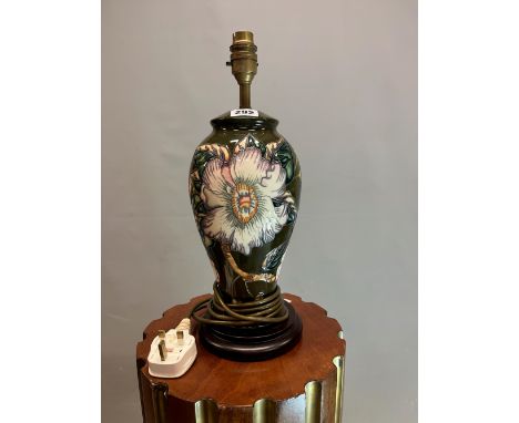 A MOORCROFT TABLE LAMP, THE BALUSTER BODY SLIP TRAILED WITH SPIKEY FLOWERS ON A DEEP GREEN GROUND.   H 38cms.