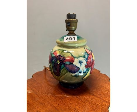 A MOORCROFT COMPRESSED SPHERICAL TABLE LAMP SLIP TRAILED WITH IRISES AND OTHER FLOWERS AGAINST A SHADED BLUE/GREEN GROUND.   