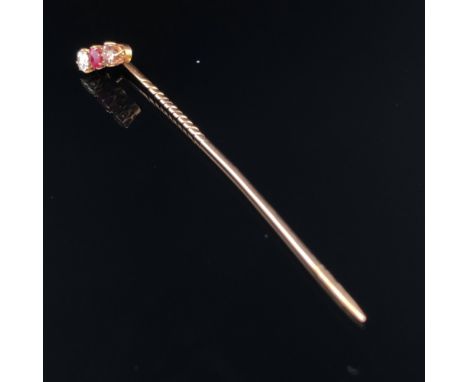 A DIAMOND AND RUBY STICK PIN. THE THREE GEMS SET IN CLAW SETTINGS UPON A TRADITIONAL PIN. UNHALLMARKED, ASSESSED AS 14ct GOLD