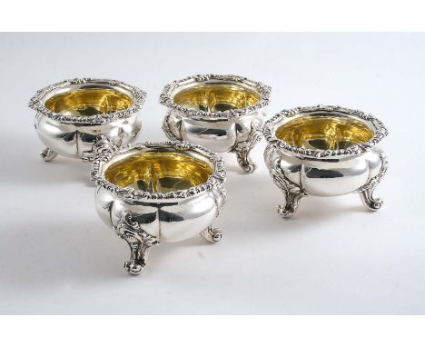A SET OF FOUR EARLY VICTORIAN SALTS of shaped circular outline on three decorative scroll feet with gadroon & foliate borders