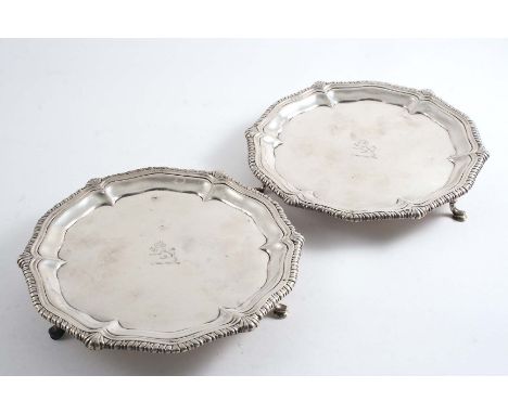 A PAIR OF GEORGE II WAITERS of shaped circular outline with gadroon & shell borders and hoof feet, crested* and each with a s