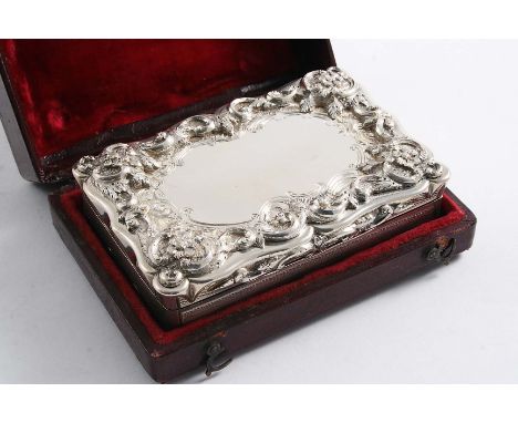 A VICTORIAN SNUFF BOX of shaped oblong outline with applied, chased floral scrolls around the cover in relief, the base with 
