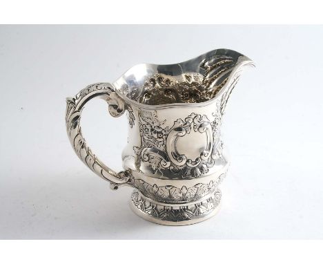 AN EDWARDIAN WATER JUG OR PITCHER  with embossed decoration, a shaped rim & a vacant cartouche on each side, by G. Nathan & R