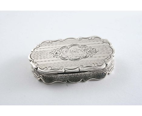 A VICTORIAN VINAIGRETTE of shaped oval outline with engine-turned decoration and a floral scroll cartouche on the cover, insc