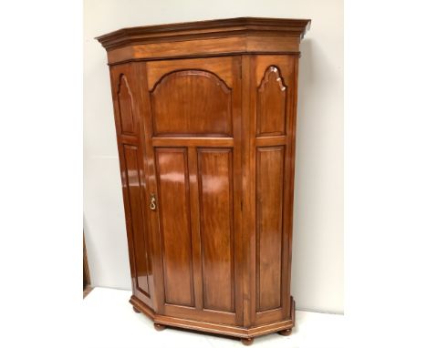 A Victorian walnut hall cupboard with canted corners, raised and fielded panels to the front, brass coat hooks, ornate stick 