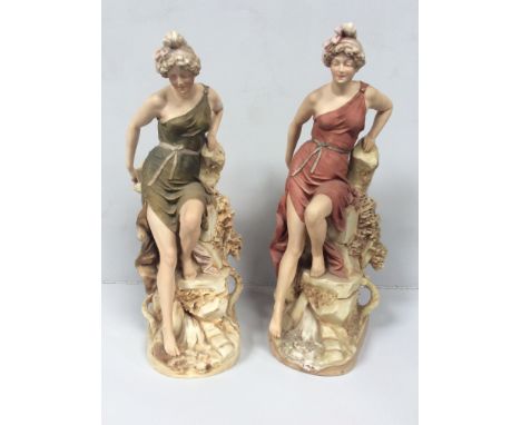 Two matching Royal Dux porcelain figural spill vases modelled as classical maidens, each sat atop a rocky outcrop, one with s