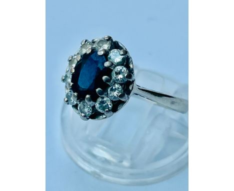 An 18ct white gold sapphire and diamond cluster ring, set with and an oval sapphire surrounded by 10 x round brilliant cut di