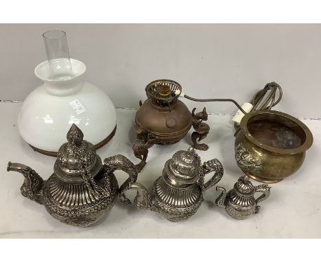 A Tibetan white metal set of graduated teapots with chains attaching covers, together with a small brass oil lamp with white 