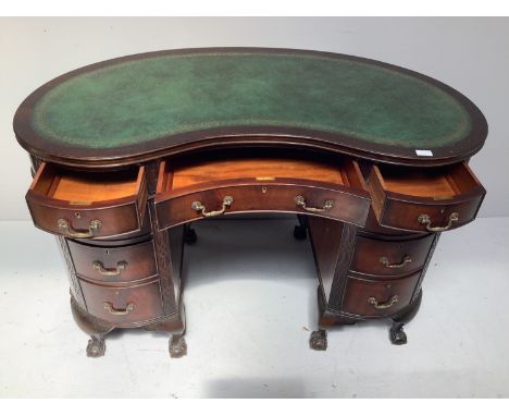 An Edwardian stained mahogany kidney shaped desk, the gilt-tooled green leather top, above three frieze drawers and two banks