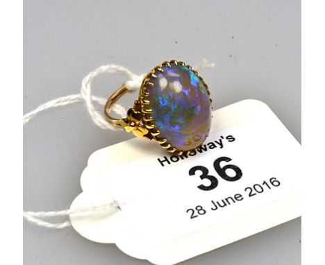 A single stone opal ring, the large oval opal in multiple claw mounts to gold floral shoulders and reeded shank