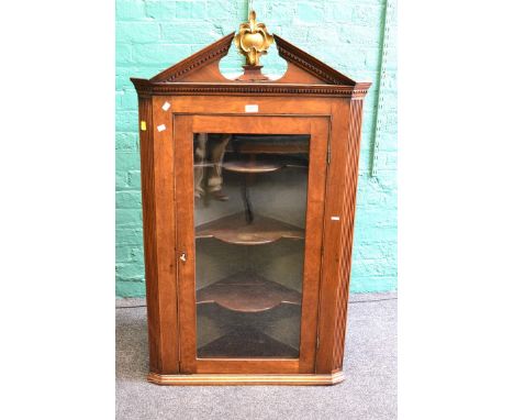 A George III mahogany hanging corner cupboard, with single glazed door and broken architectural pediment and gilt finial, 75c