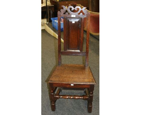 An early 18th century oak Lancashire type back stool, with shaped and pierced crest and panel back over solid seat and turned