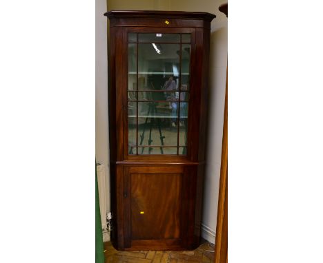 A 19th century mahogany floor standing corner cupboard, the moulded cornice over glazed door enclosing two shelves above a pa