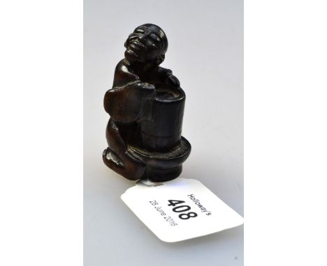 A Japanese 19th century carved ebony netsuke, in the form of a seated South Sea Islander, seated at a tribal drum, 5.5cm high