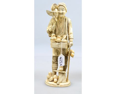 A late 19th century Japanese ivory okimono, carved as a toy seller, holding a puppet, with tray slung from his shoulders supp