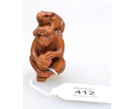A Japanese 20th century carved boxwood netsuke, in the form of a monkey seated with a large persimmon in his paws and a rat p