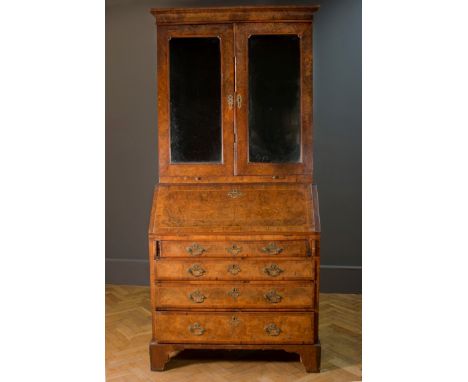 A George I figured walnut bureau bookcase, the upper section with shaped and bevelled Vauxhall type plates enclosing a fitted