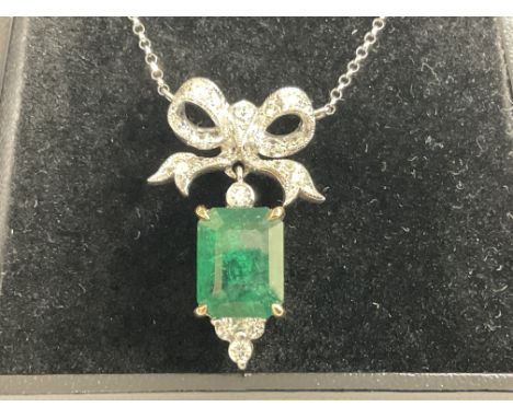 18ct white and yellow gold pendant set with a step cut emerald with RBC diamonds set below, and a diamond set large bow bale 