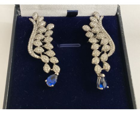 Pair silver fancy long drop earrings set with clusters of white cubic zirconia, and suspended pear shaped blue cubic zirconia