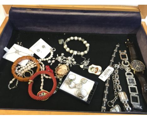 A display case containing silver pearls, cameo, Wade porcelain Tommy Steele brooch, red coral bracelet. This lot cannot be po