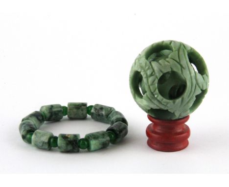 A Chinese carved green jade and green cornelian bracelet and carved ball in ball.