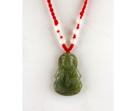 A carved olive green jade amulet of the goddess Guanyin on a red silk adjustable neck cord, pendant H. 3.5cm.