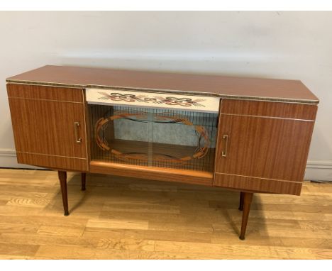 A 1950's drinks cabinet/sideboard, central drawer, flanked by two cupboards with central glazed sliding doors to reveal fitte