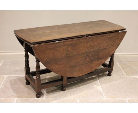 An 18th century and later oak drop leaf dining table, the oval top above a pair of opposing frieze drawers, raised upon balus