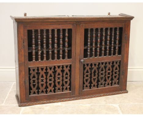 An 18th century Welsh oak wall mounted food cupboard, the pair of doors with bobbin turned spindles over fretwork spindles pi