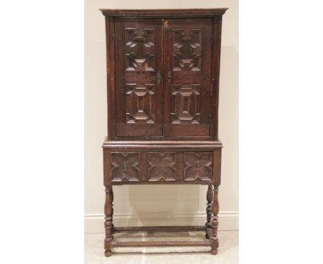 An 18th century and later Jacobean cabinet on stand, the cabinet with a moulded cornice over two doors applied with geometric