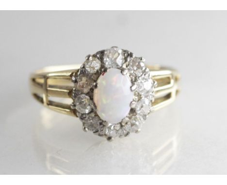 An opal and diamond cluster ring, the central oval opal measuring 7mm x 5mm, with a cluster surround of ten old cut diamonds,