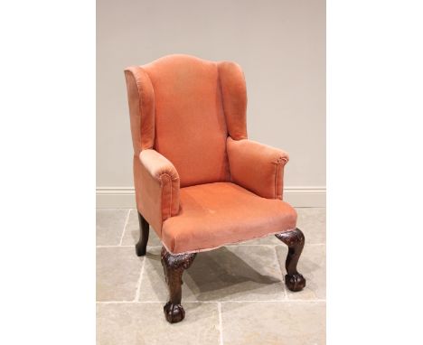 A George III style wing back armchair, 19th century, upholstered in pink velour, the camel back extending to padded wing back