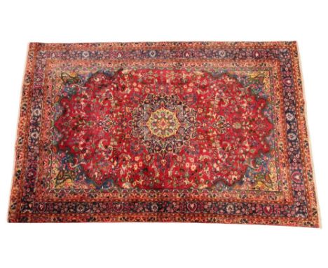 A red ground Persian fabriz carpet with Shabaz medallion, in red, green and blue colourways, the blue tipped spandrels enclos
