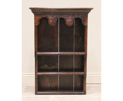 An 18th century and later constructed oak hanging wall shelf, with a moulded cornice above a lobed frieze and three enclosed 