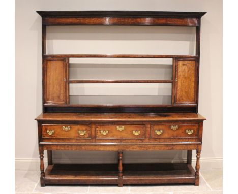 A George III oak pot board dresser, the plate rack with a moulded cornice over three shelves flanked by spice cupboards, upon