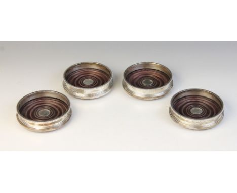 A set of three silver mounted coasters, William Comyns, London 1985, each of circular form with turned mahogany bases, plain 