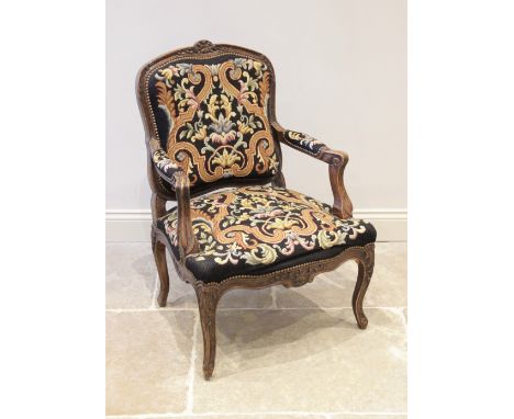 A Louis XV style fauteuil, mid 20th century, upholstered in tapestry fabric, the carved stained beech wood frame extending to