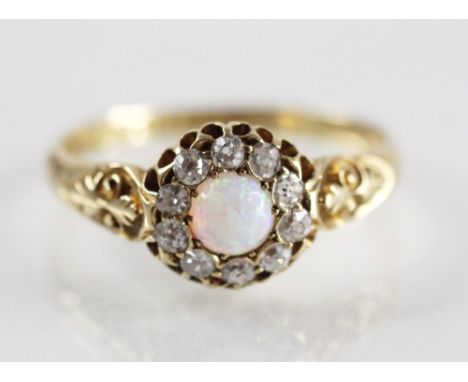 A Victorian opal and diamond 18ct gold cluster ring, the central opal cabochon measuring 5mm diameter, with a surround of ten