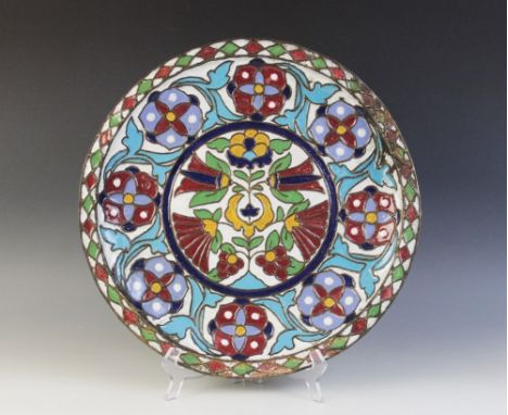 An Islamic influence enamelled copper charger, of circular form, decorated in floral motifs with polychrome enamel, 37cm wide