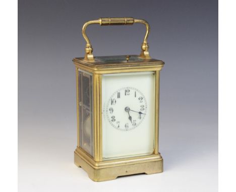An early 20th century brass cased repeater carriage clock, with a swing handle and repeater button above a 6cm off white enam